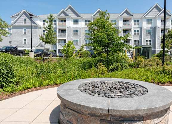 a stone fire pit in front of an apartment building