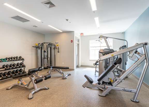 a gym with weights and dumbbells in the corner of a room