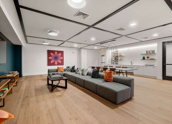 A modern living room with a grey sofa and a wooden floor.
