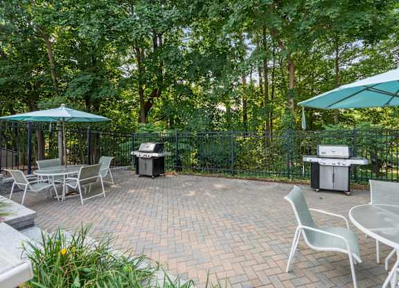 A patio with a table and chairs and a grill.