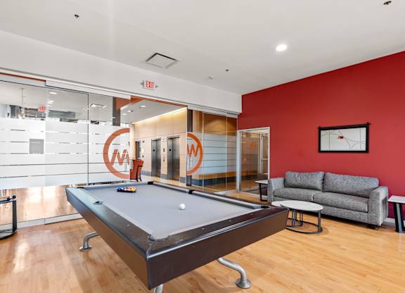 A pool table is in the middle of a room with a couch and a coffee table.