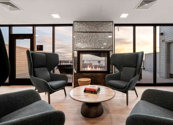 A living room with a fireplace and grey chairs.