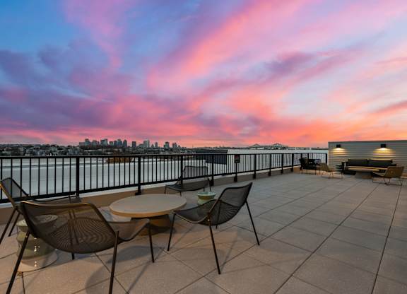 A patio with a couch, chairs, and a television on a building.
