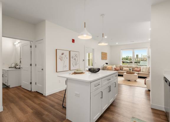 A modern kitchen with white cabinets and a wooden floor.