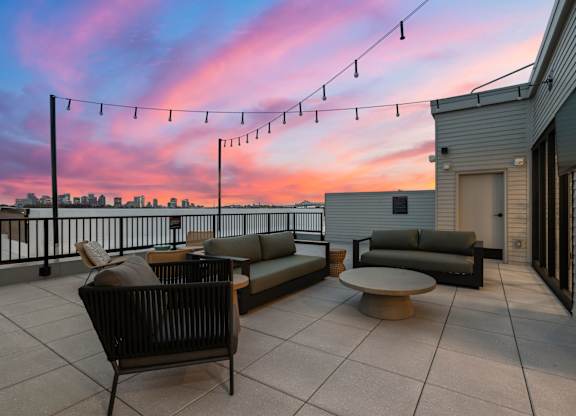 A patio with furniture and string lights is set against a twilight sky.