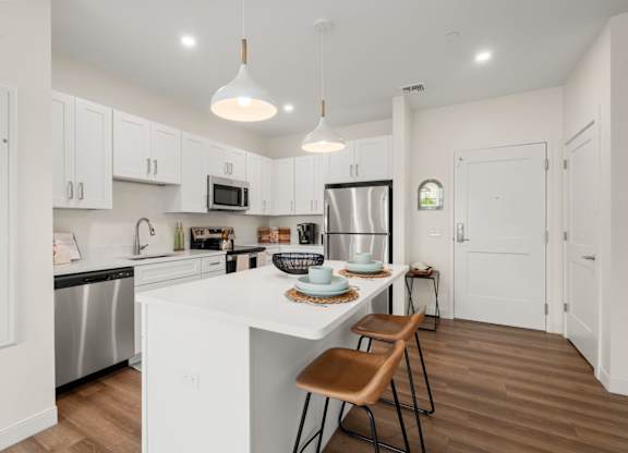 A modern kitchen with white cabinets and a wooden table.