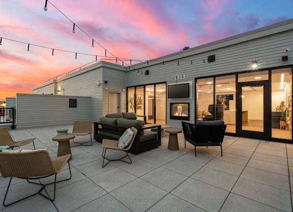 A patio with a couch, chairs, and a television on a building.