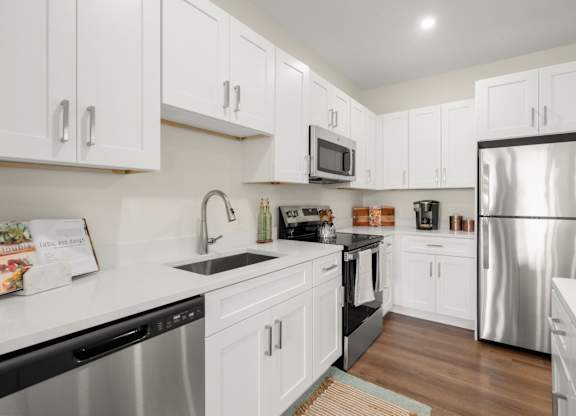 A kitchen with white cabinets and a stainless steel refrigerator.