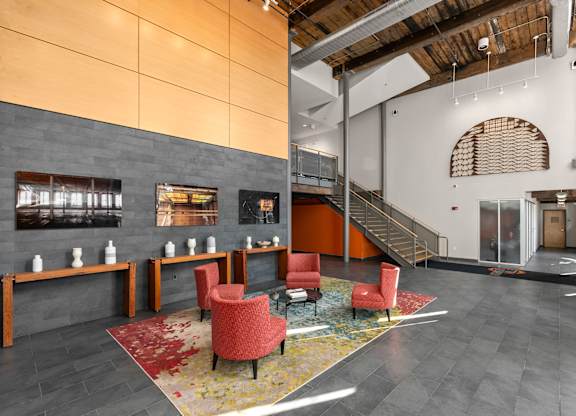 A modern lobby with a staircase and a red chair.
