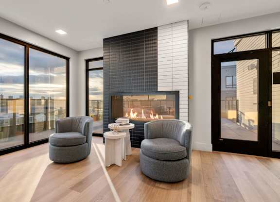 A modern living room with a fireplace and two grey armchairs.