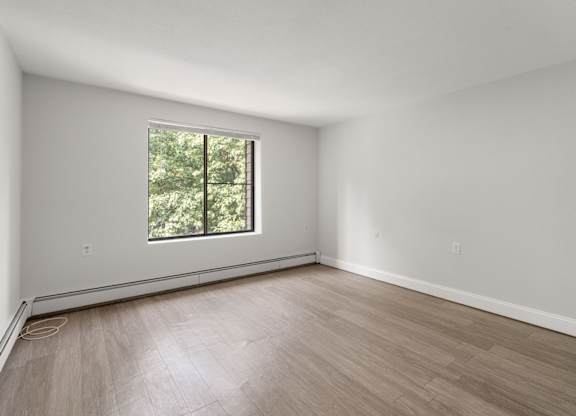 A room with a window and wooden flooring.