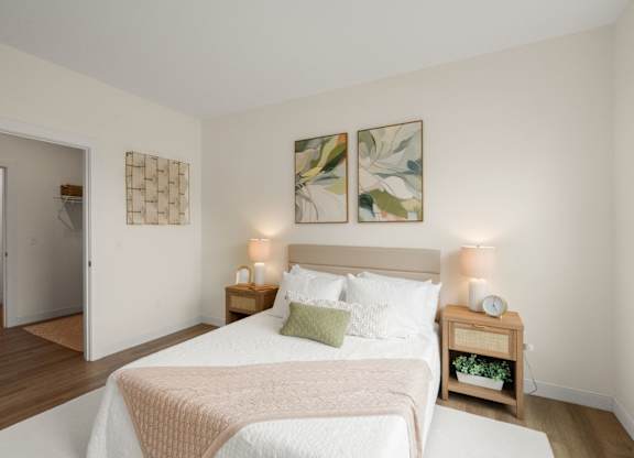 A bedroom with a bed, nightstand, and two wall art pieces.