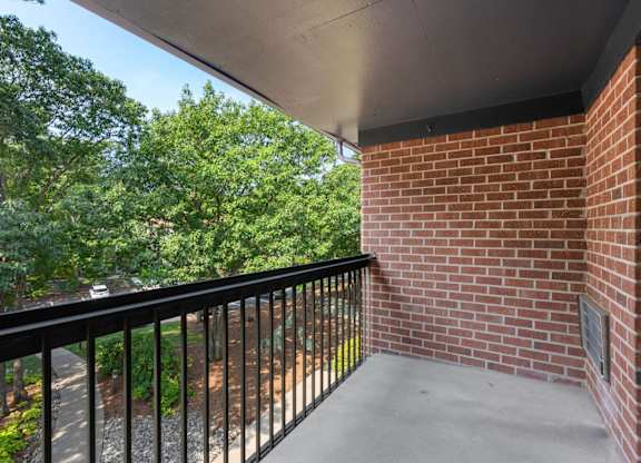 A balcony with a black railing and a brick wall.
