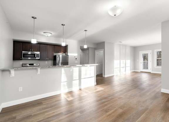 Ashland woods apartments in massachusetts with open floor plans, kitchen in background and living room with large windows.