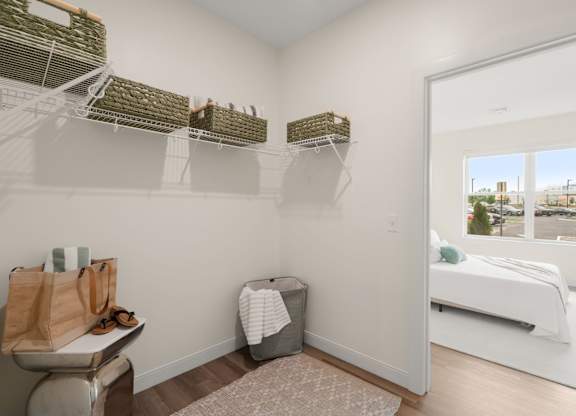 A bedroom with a white bed and a window overlooking a cityscape.