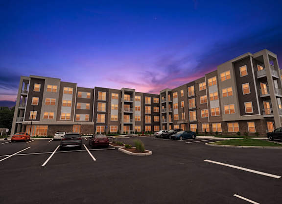 A parking lot in front of a large apartment building.