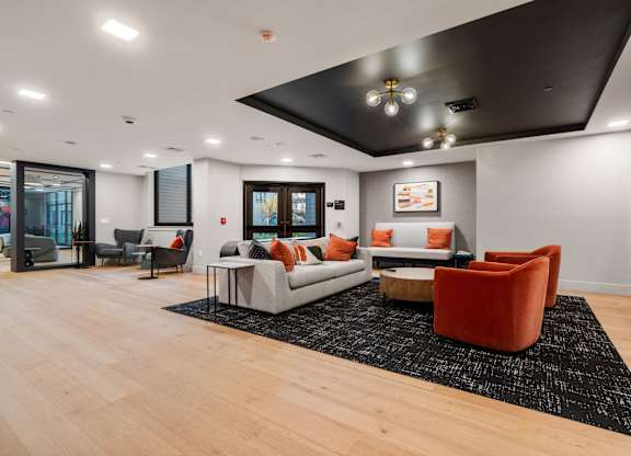 A living room with a grey couch and orange chairs.