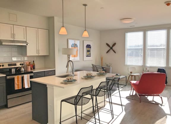 Model apartment kitchen with overhead lights, white counters and breakfast bar