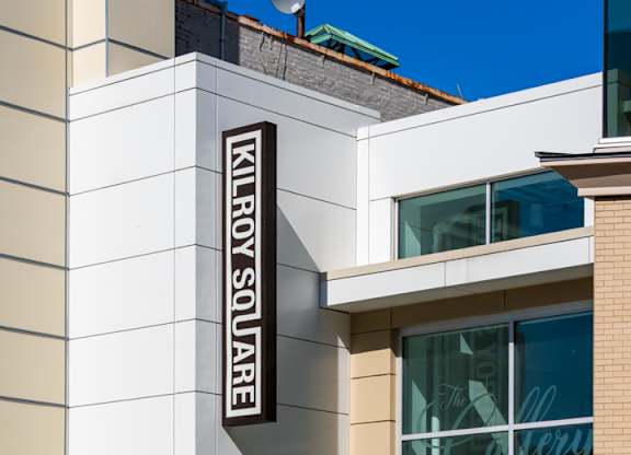A building with a white facade and a sign that says Killroy Square.