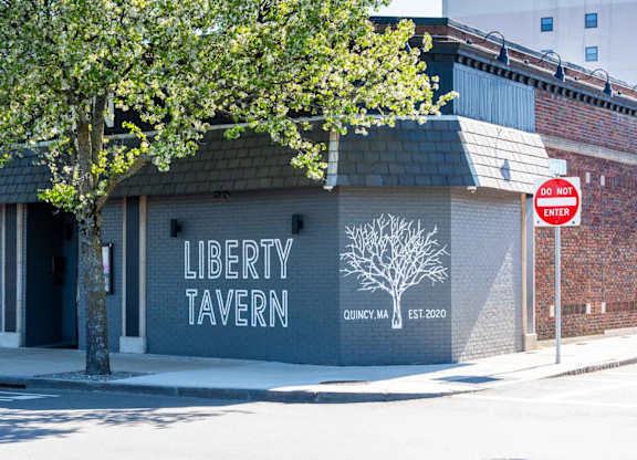 A white tree stands in front of a brick building with a sign that says