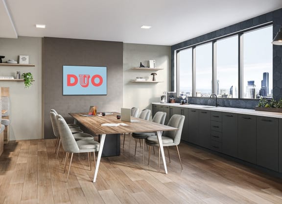 Amenity lounge with views of the city skyline, conference table seating with a tv at the end of the table, and booth seating.