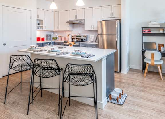 A kitchen with a table and chairs in front of it in model apartment at the Mastlight.
