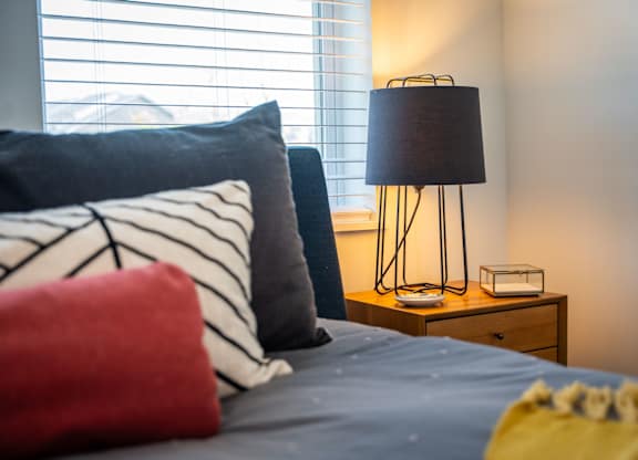 A bed with a red pillow and a lamp on a side table at the Mastlight.