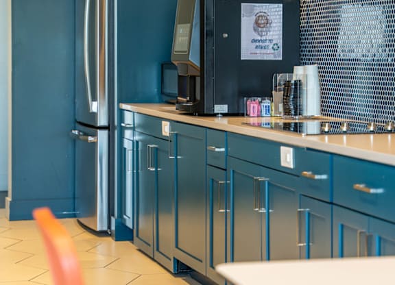 Mastlight apartment kitchen with blue cabinets and a white table.