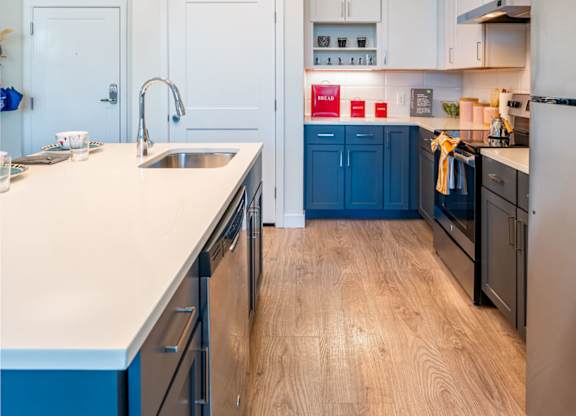 A kitchen with a white counter top and blue cabinets at the Mastlight.