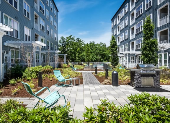 a patio with a fire pit and lounge chairs in front of a building