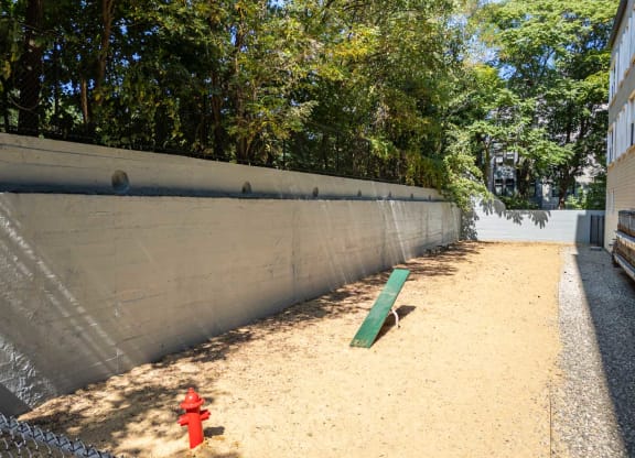 a red fire hydrant sitting in the sand next to a fence