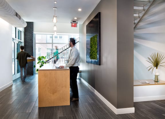 a man in a white shirt and black pants stands at the front desk of an office