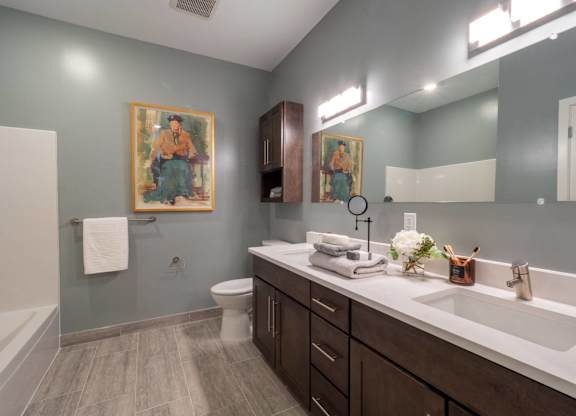 A bathroom with a toilet, sink, and a painting on the wall.
