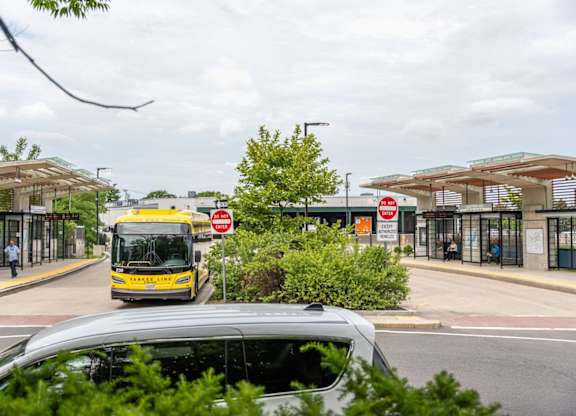 A bus is driving down a street past a bus stop.