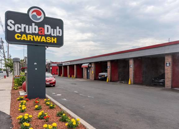A Scrubadub Carwash sign is in front of a car wash.