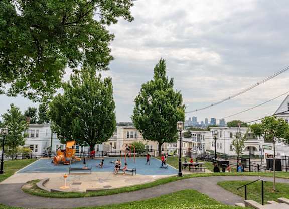 A playground with a slide and swings surrounded by trees and a fence.