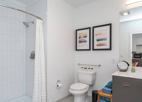 A white toilet sits next to a white shower curtain in a small bathroom.