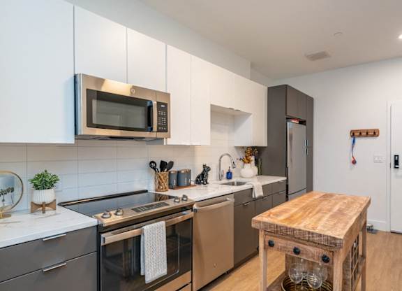 A modern kitchen with a wooden table and stainless steel appliances.