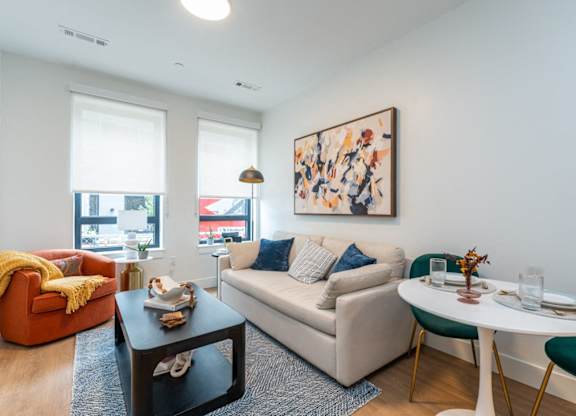 A living room with a white couch, a green chair, and a painting on the wall.