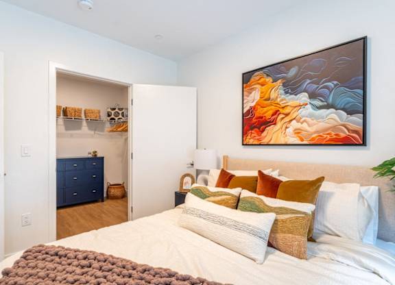 A bedroom with a large bed and a painting on the wall.