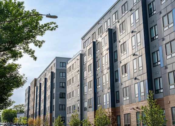 A row of modern apartment buildings with trees in front.