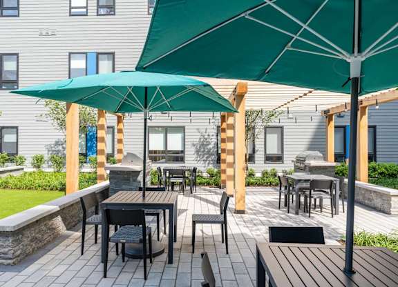 A patio with a table and chairs under a green umbrella.