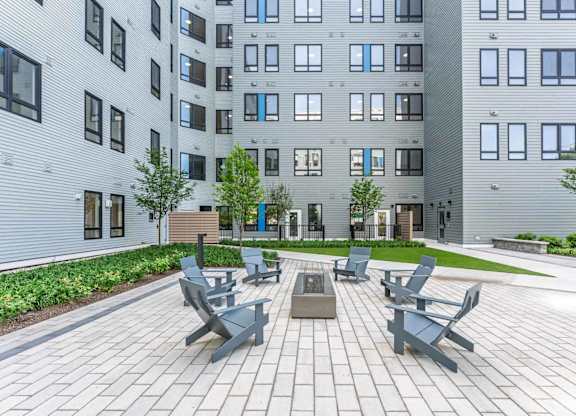A modern courtyard with benches and a tree in front of a building.