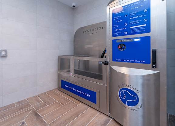 A stainless steel dog wash station with a blue sign that says