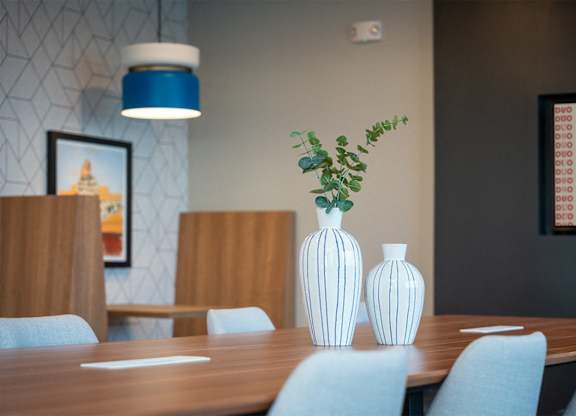 A dining table with two vases and a plant on it.