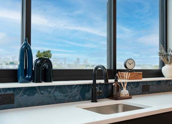 A kitchen with a large window overlooking a cityscape.