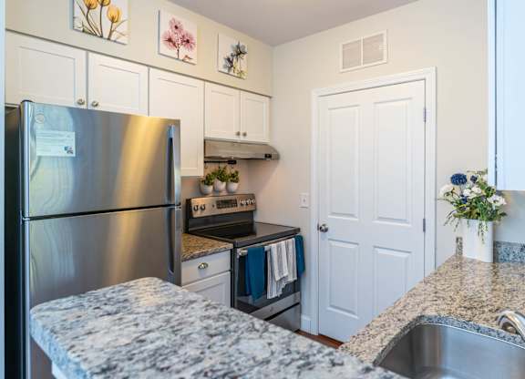 Parkside Commons white cabinetry kitchen with a granite countertop and stainless steel appliances.