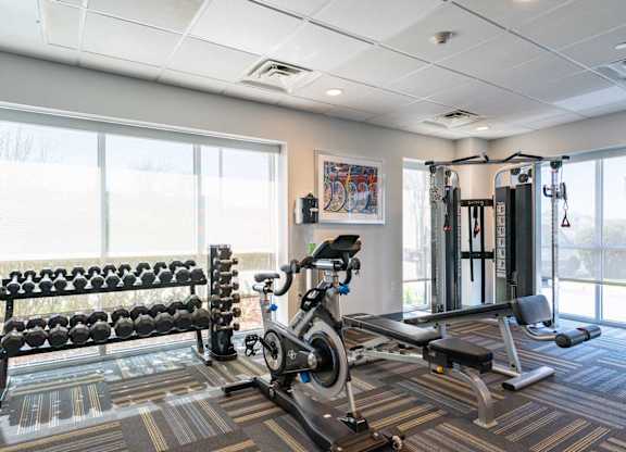 Chelsea Place gym with a row of dumbbells, a bench, a stationary bike, and a squat rack.