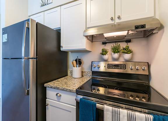 Parkside Commons kitchens with white cabinets, a refrigerator is next to a stove in a kitchen.