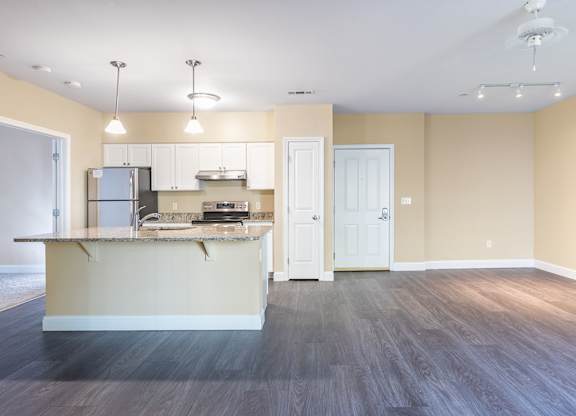 A kitchen with a refrigerator, sink, and cabinets.